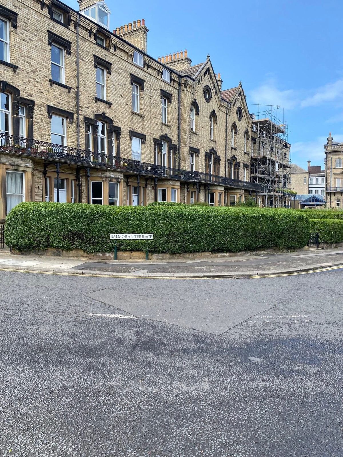 A neatly clipped hedge in front of a Victorian stone terrace
