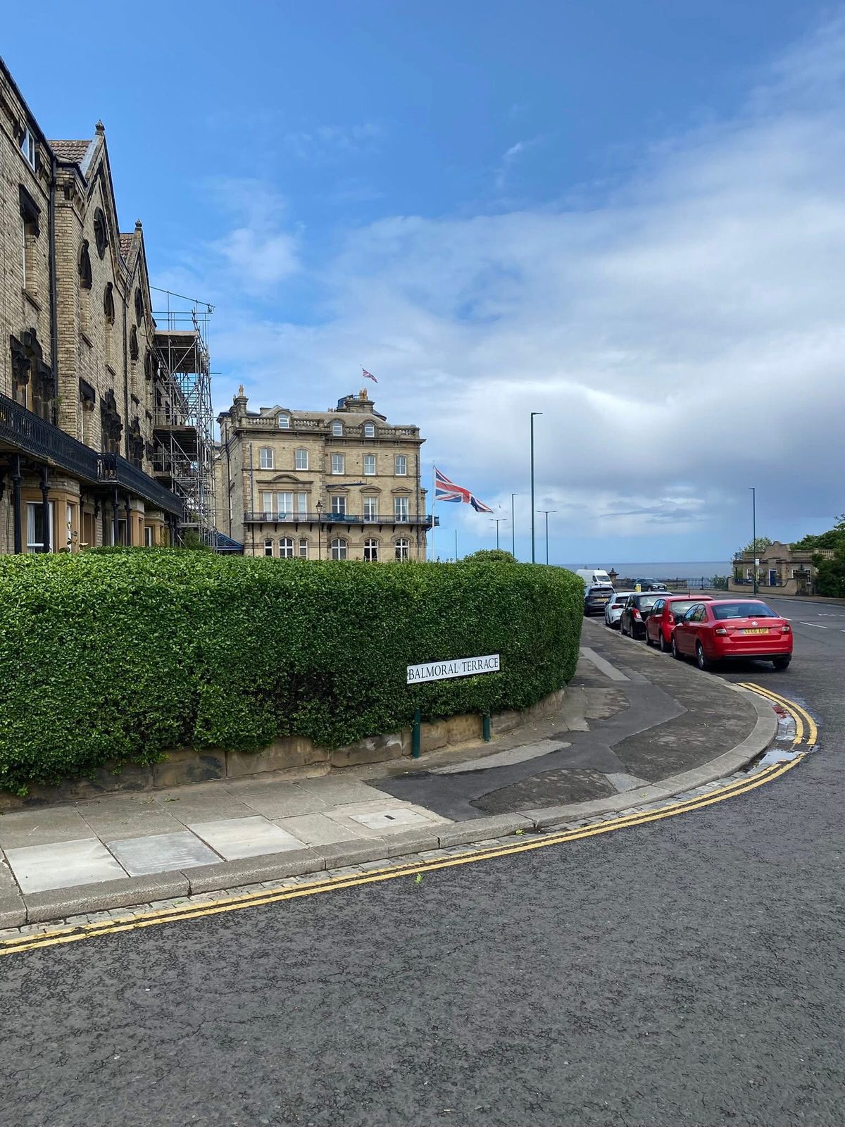 A clipped hedge following the curve of a street corner by the sea